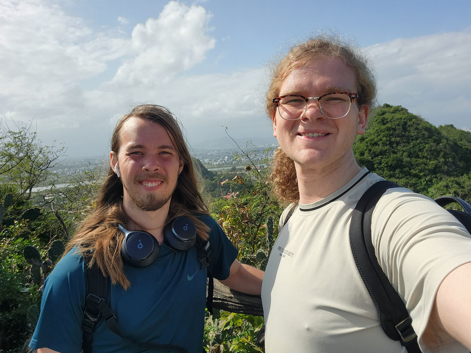 Damian and cousin, smiling on a mountaintop with a view of a city skyline.