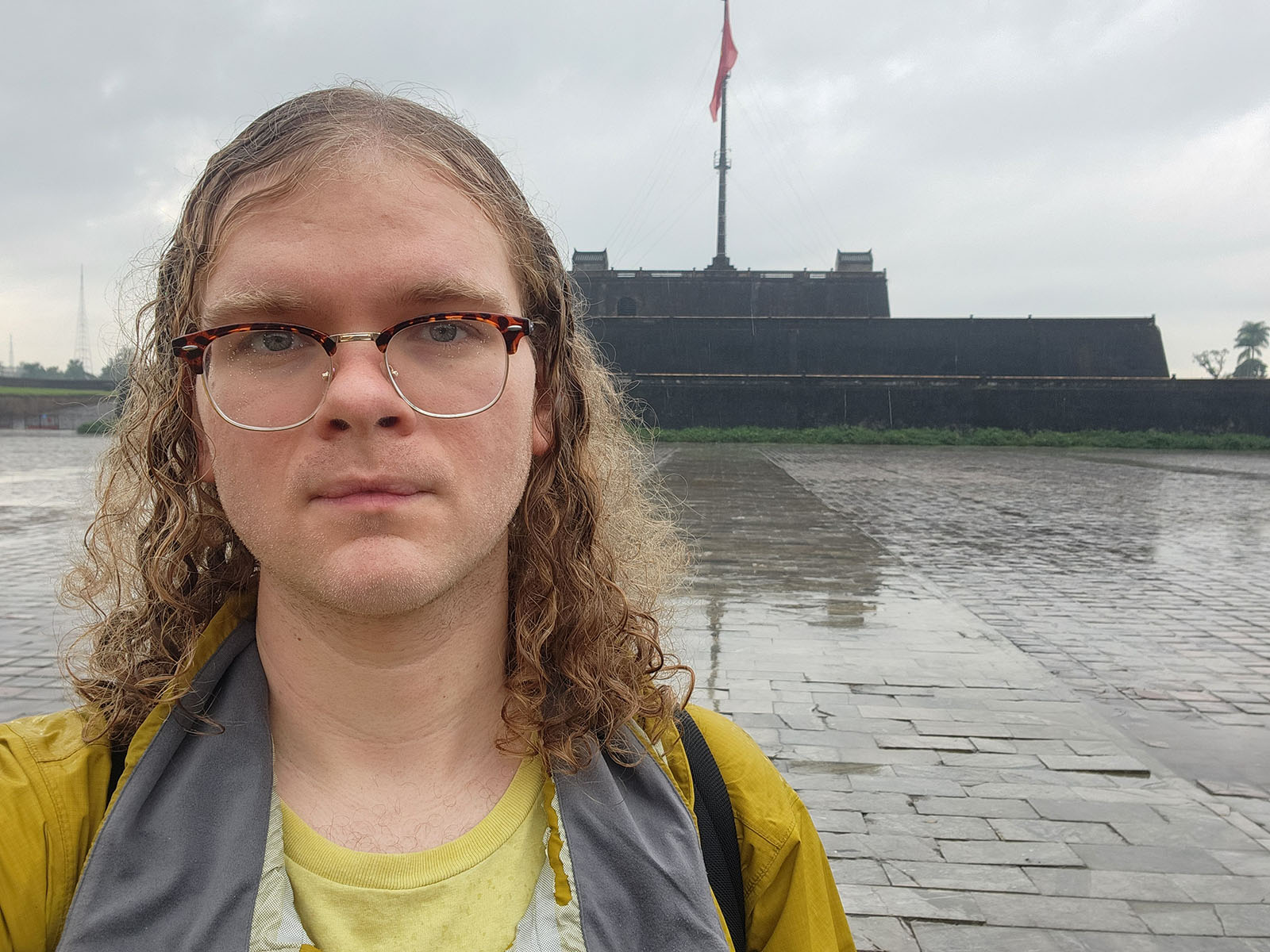 Damian's selfie in front of a bunker-like structure with a tall flag atop.