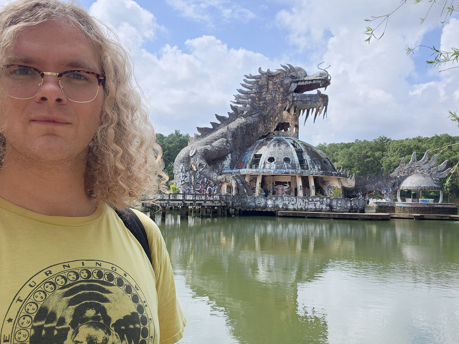 Damian's selfie in front of a decayed two-story dome structure with a large, hollow dragon circling it and perched atop it. The inside of the dragon's mouth is an observation tower.