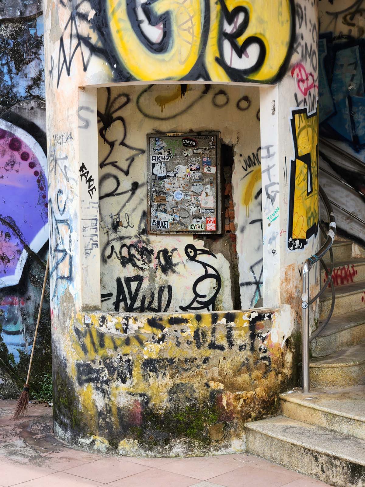 A graffiti-covered circular booth or kiosk with a rectangular access window.