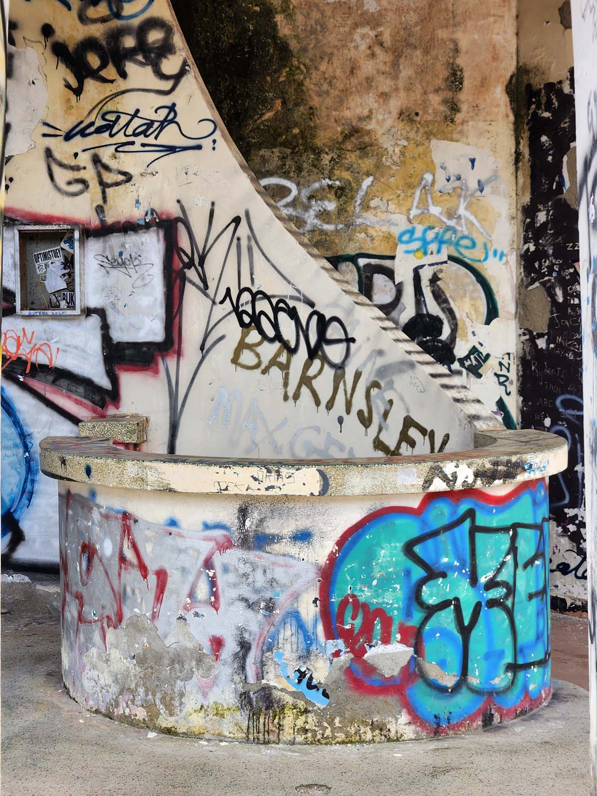 A graffiti-covered circular booth or kiosk with an open desk/countertop structure.