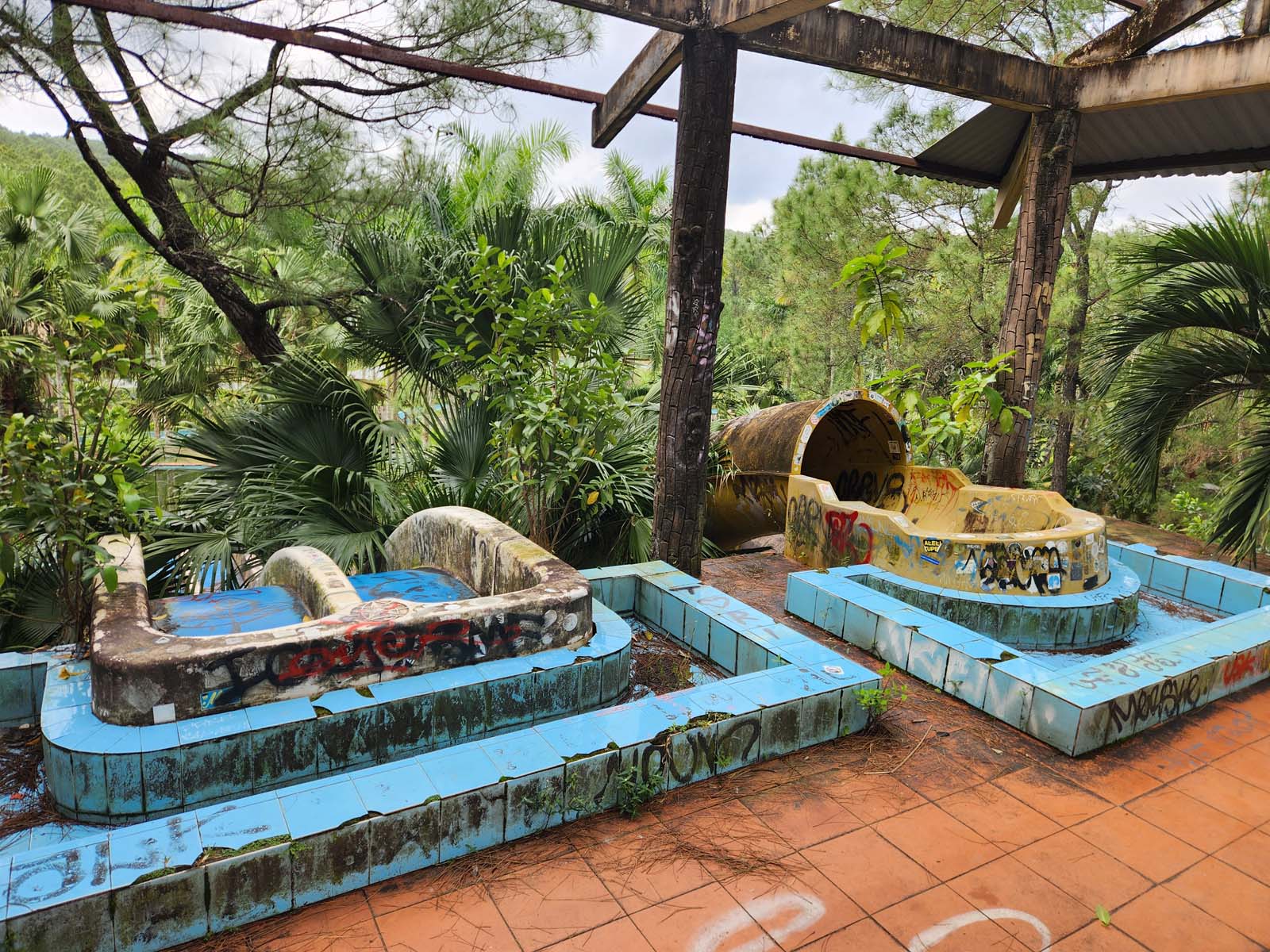 A photo of the tops of the water slides, with impenetrable thickets of palm and banana trees obscuring the landing pool below.