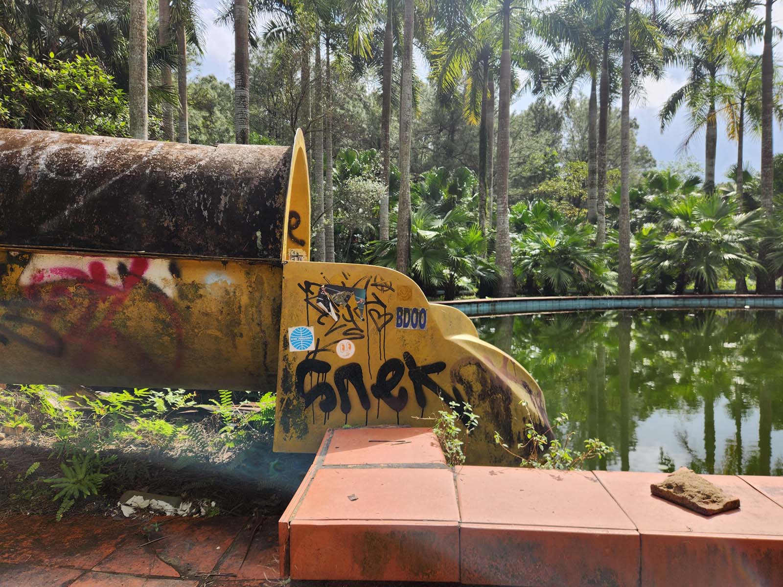 A side-view picture of the bottom of a waterslide. Someone has written 'Snek' in graffiti.