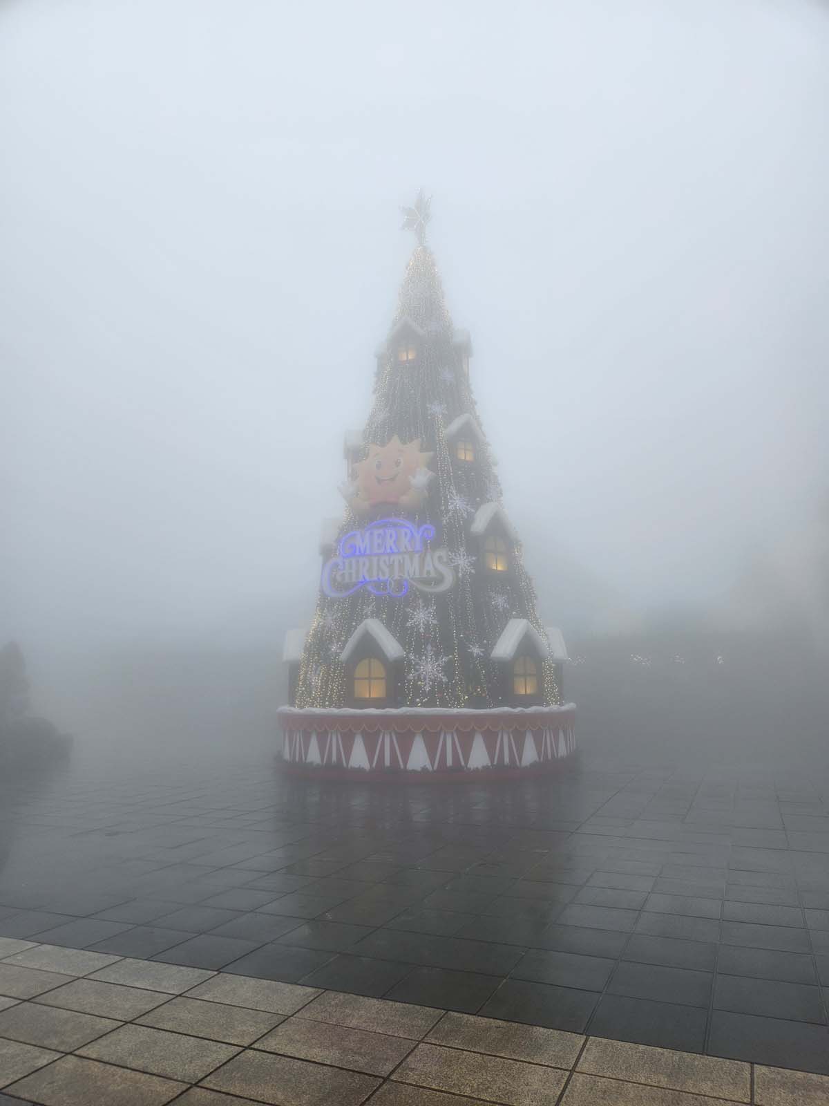 A large faux Christmas tree obscured by mist.