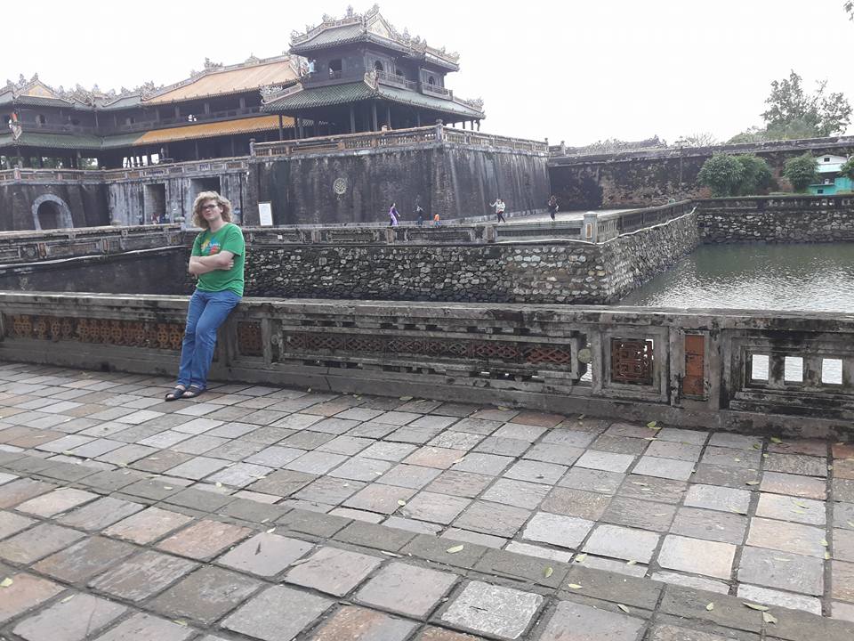 Damian leaning on a concrete half-wall backdropped by the Imperial City and its moat.