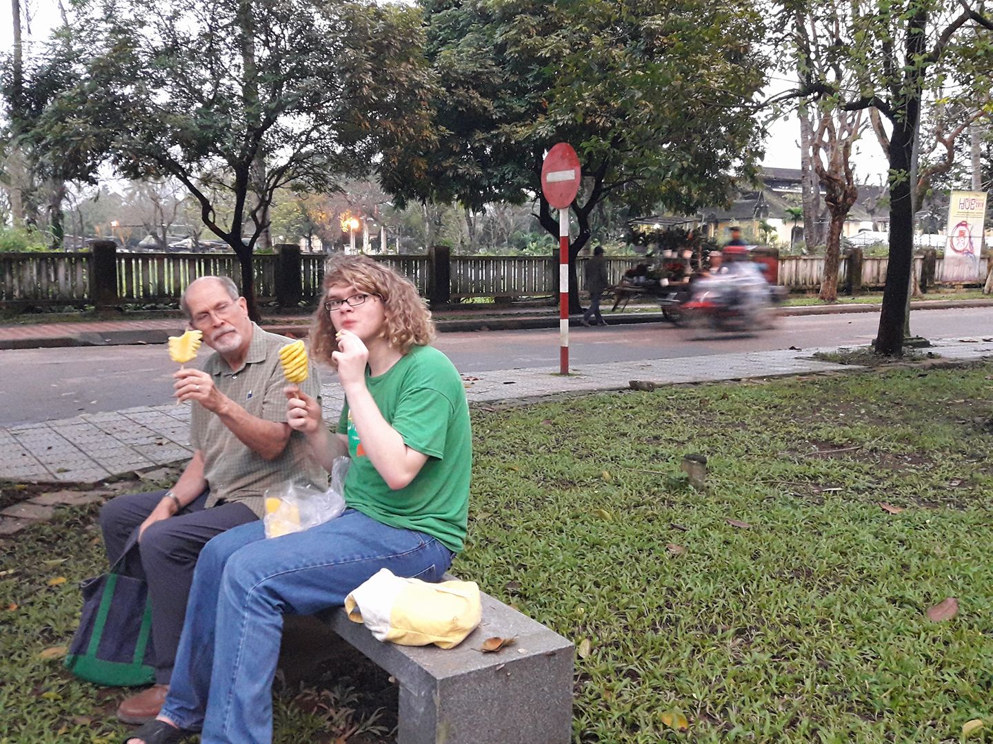 A photo from 2018 of Damian and Grandpa Mike eating pineapples on a street corner.