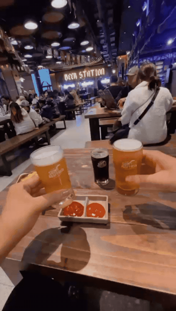 A boomerang of Damian and Ben clinking small glasses of beer together.